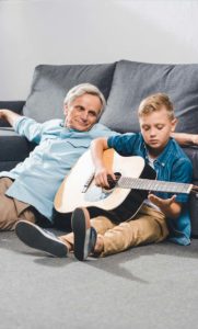 grandparent on floor watching grandson play guitar
